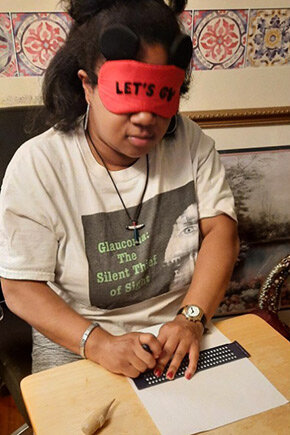 Glaucoma patient Jasmyn wearing blindfold and practicing reading Braille with her hands