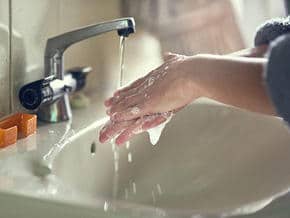 photo of a woman washing hands with soap and water in a sink