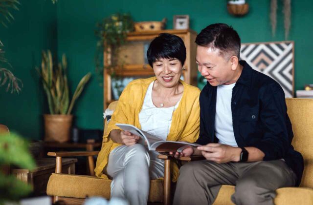 Asian Couple Reading A Booklet Together In Their Home