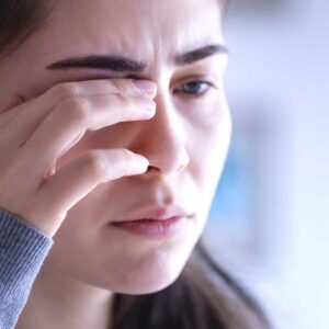 woman with eye pain rubs her eye