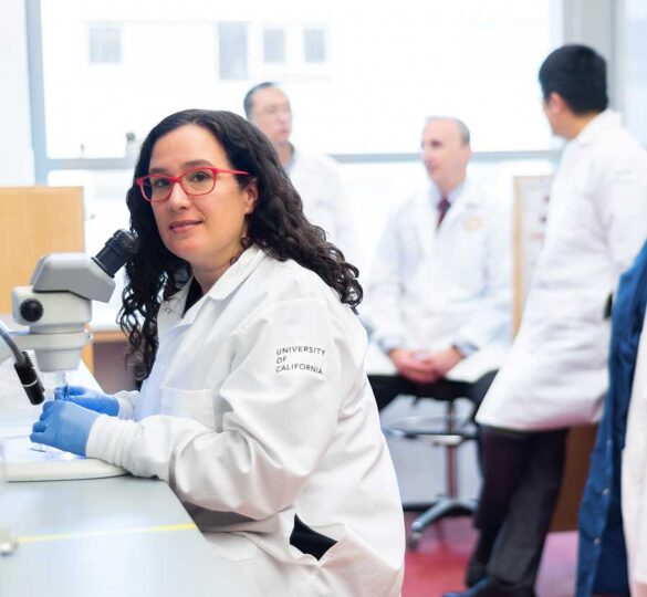 Anna La Torre, PhD at the microscope, with the other three Catalyst for a Cure researchers in the background